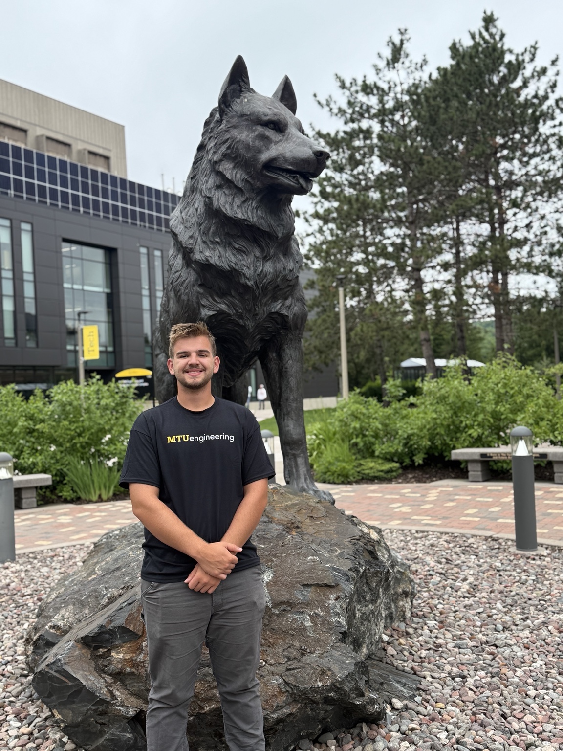 Nathaniel Skiera standing by the Michigan Tech Husky statue